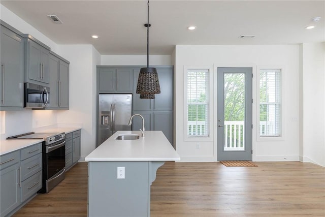 kitchen with light wood finished floors, visible vents, gray cabinetry, appliances with stainless steel finishes, and a sink