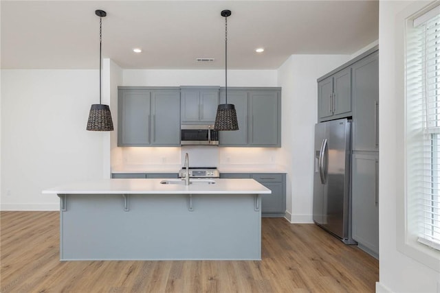 kitchen featuring light countertops, a kitchen breakfast bar, gray cabinets, and stainless steel appliances