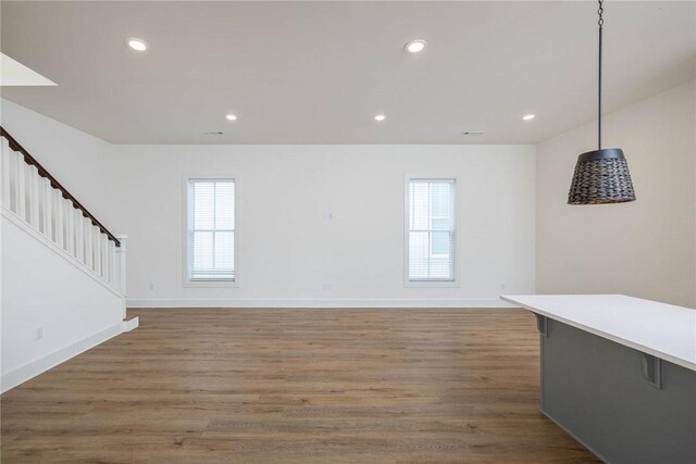 unfurnished living room with stairway, recessed lighting, baseboards, and wood finished floors