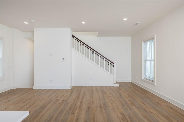 unfurnished living room with recessed lighting, stairs, and wood finished floors