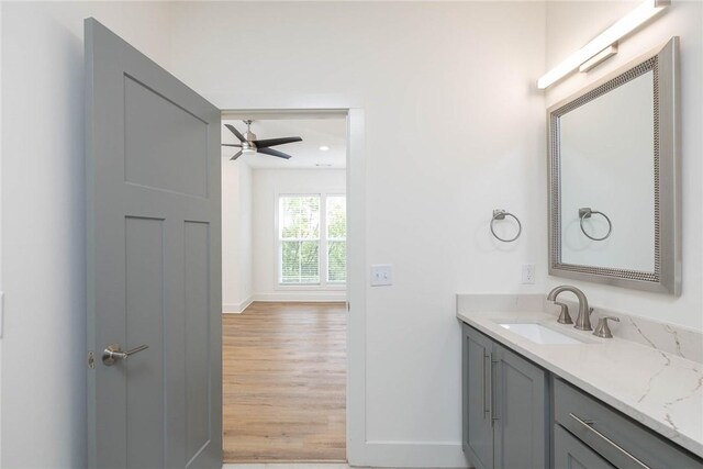 bathroom featuring baseboards, wood finished floors, ceiling fan, and vanity