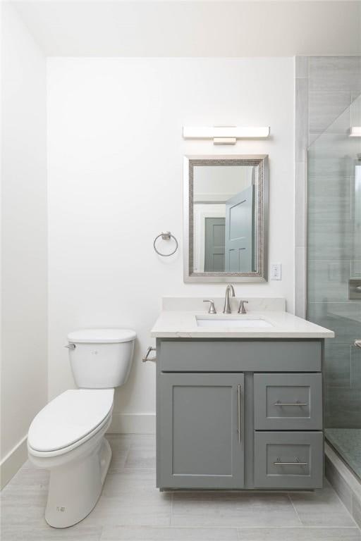 full bath featuring vanity, toilet, baseboards, and a stall shower