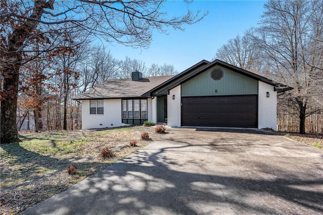 view of front of property with a garage, brick siding, concrete driveway, and a chimney