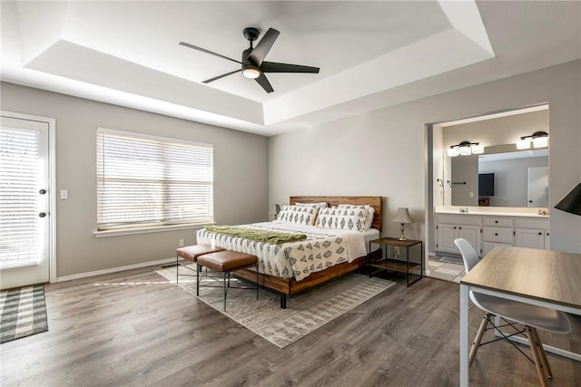 bedroom featuring a tray ceiling, multiple windows, and wood finished floors