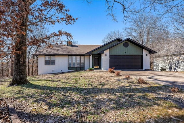 view of front of house featuring a front yard, driveway, a chimney, a garage, and brick siding