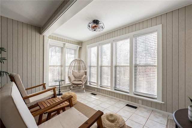 sitting room featuring tile patterned floors, visible vents, wood walls, and beam ceiling