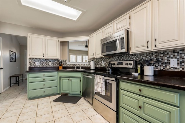 kitchen featuring light tile patterned floors, stainless steel appliances, dark countertops, and a sink