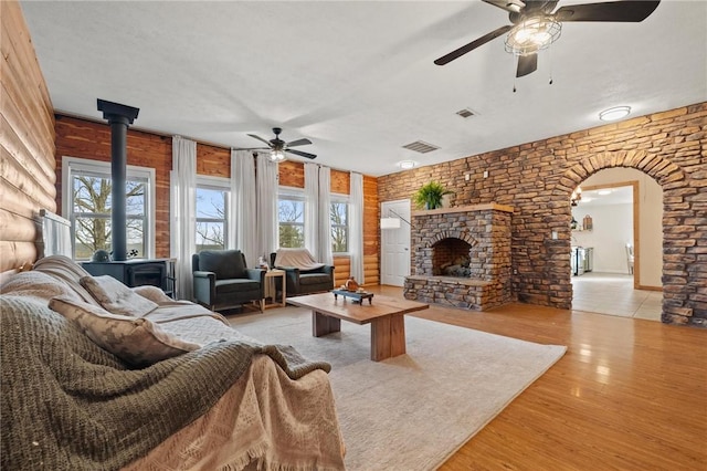 living area featuring wood finished floors, visible vents, a wood stove, a fireplace, and arched walkways