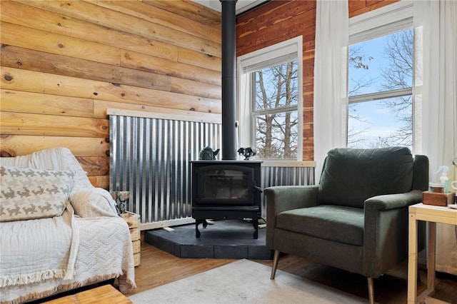 bedroom with a wood stove, wood finished floors, and log walls