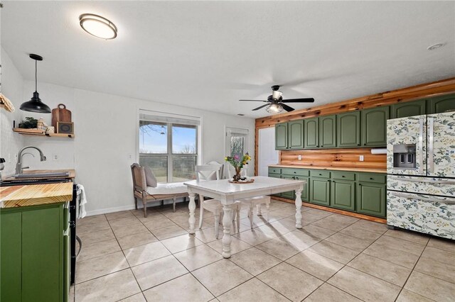 kitchen featuring refrigerator with ice dispenser, a sink, green cabinets, butcher block counters, and light tile patterned floors