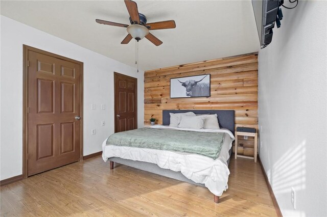 bedroom with rustic walls, a ceiling fan, light wood-type flooring, and baseboards