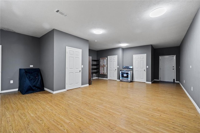 unfurnished living room featuring visible vents, light wood-type flooring, and baseboards