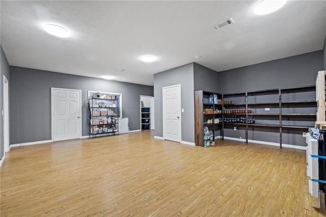 unfurnished bedroom featuring visible vents, baseboards, a textured ceiling, and wood finished floors