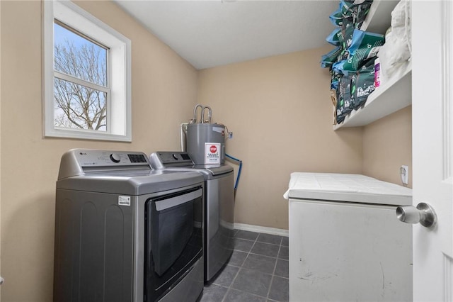 laundry area featuring baseboards, washing machine and clothes dryer, laundry area, electric water heater, and dark tile patterned floors