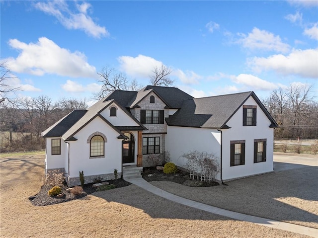 view of front of house with stone siding, stucco siding, driveway, and roof with shingles