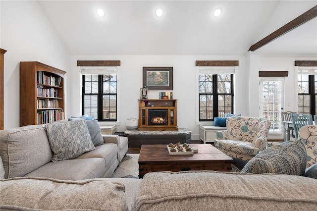 living room with a wealth of natural light, a glass covered fireplace, and vaulted ceiling