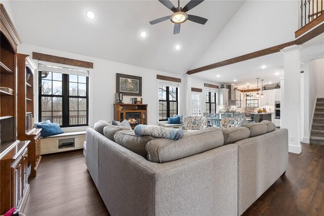 living room featuring stairway, dark wood-type flooring, a ceiling fan, and a glass covered fireplace