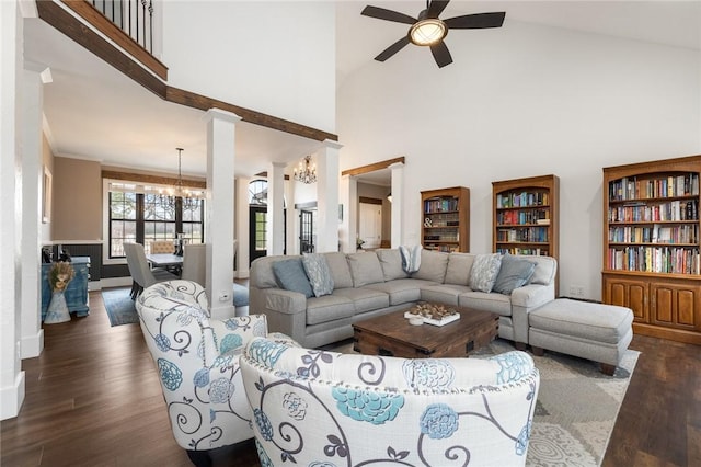 living area with dark wood-type flooring, crown molding, ceiling fan with notable chandelier, and baseboards