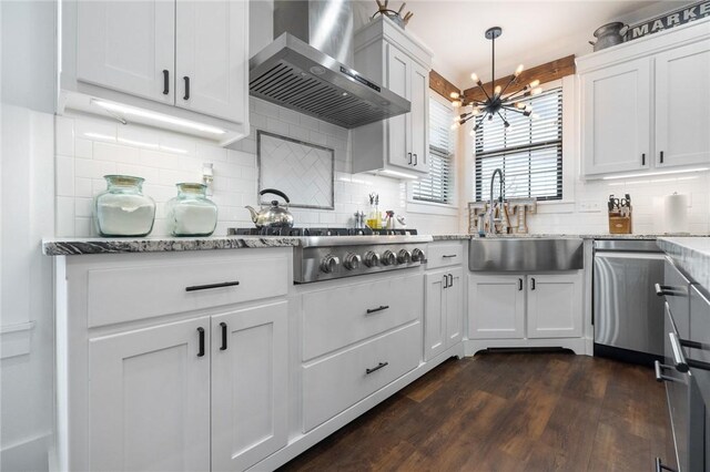 kitchen featuring a sink, dark wood finished floors, wall chimney range hood, light stone countertops, and stainless steel gas cooktop