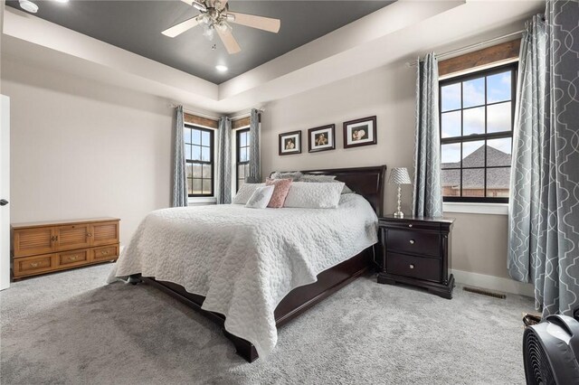 bedroom with a raised ceiling, baseboards, visible vents, and carpet floors