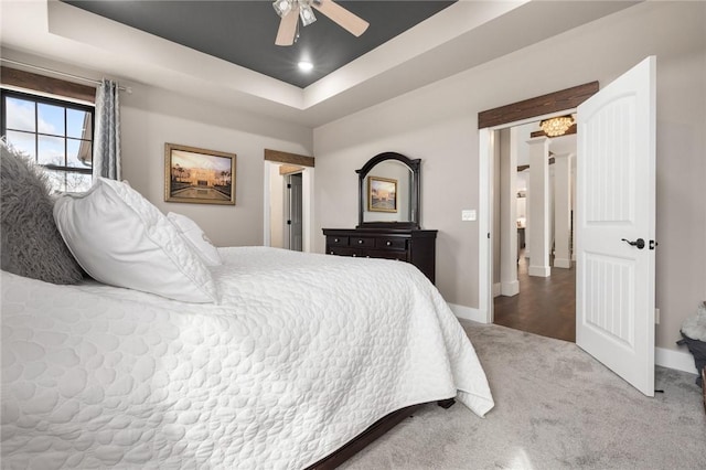 bedroom with a raised ceiling, baseboards, carpet floors, and ceiling fan