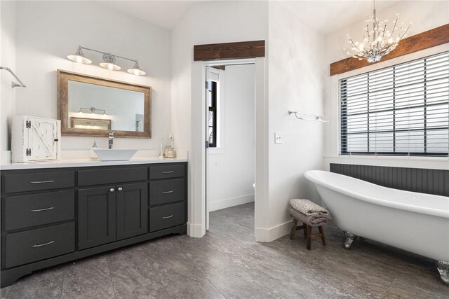 full bath with a soaking tub, an inviting chandelier, vanity, and baseboards