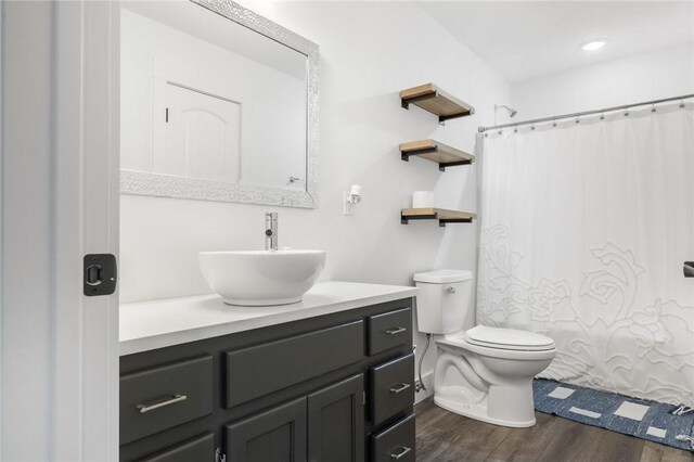 bathroom featuring curtained shower, toilet, wood finished floors, and vanity