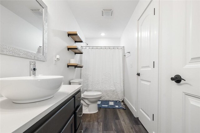 full bathroom featuring visible vents, toilet, a shower with shower curtain, wood finished floors, and vanity