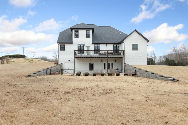 back of house with a shingled roof, a deck, and fence