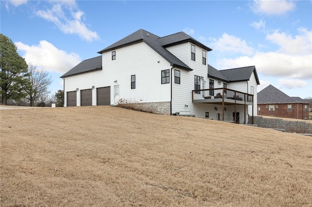 back of property featuring an attached garage and a shingled roof