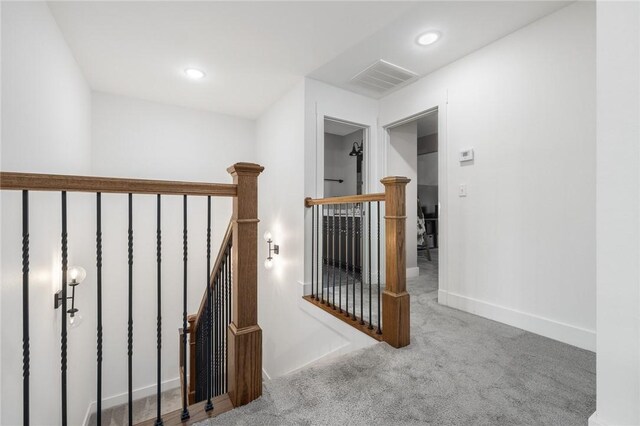 corridor with visible vents, baseboards, carpet floors, an upstairs landing, and recessed lighting