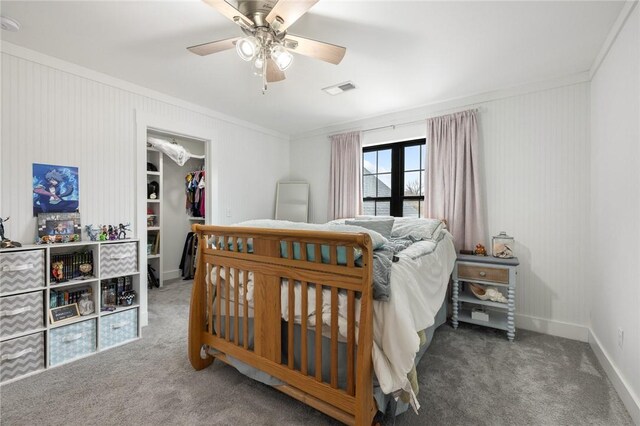 carpeted bedroom with visible vents, a walk in closet, ornamental molding, a closet, and baseboards