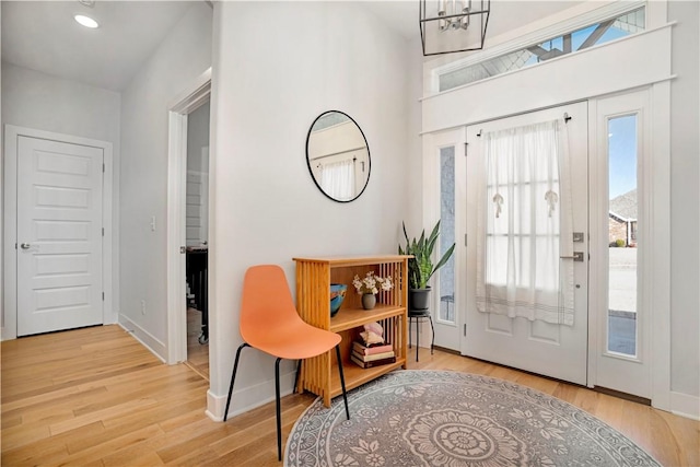 foyer entrance featuring a notable chandelier, baseboards, and wood finished floors