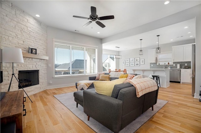 living room with ceiling fan, recessed lighting, light wood-style flooring, and a fireplace