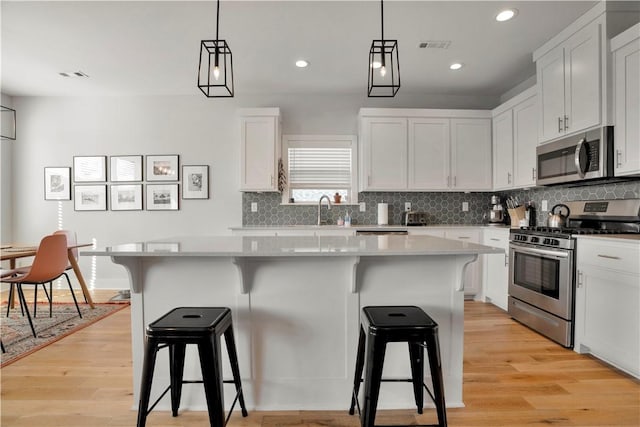 kitchen with light wood-style floors, appliances with stainless steel finishes, a breakfast bar, and a center island