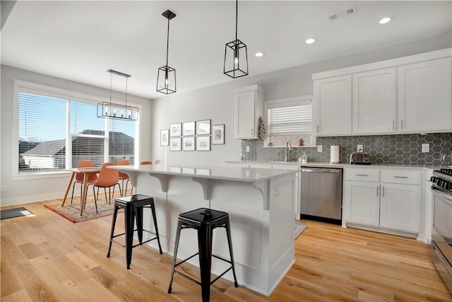 kitchen with visible vents, appliances with stainless steel finishes, a breakfast bar area, and a center island