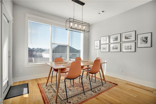 dining room featuring light wood finished floors, visible vents, and baseboards