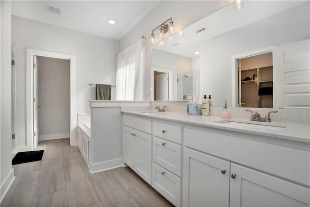 full bathroom with a sink, visible vents, a spacious closet, and a shower stall