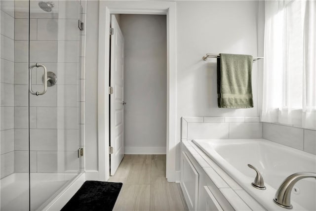 bathroom with a garden tub, baseboards, and a stall shower