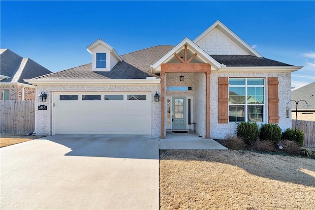 view of front of property featuring fence, an attached garage, a shingled roof, concrete driveway, and brick siding