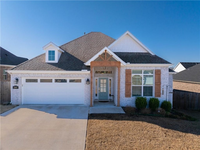 view of front of home featuring brick siding, an attached garage, driveway, and fence