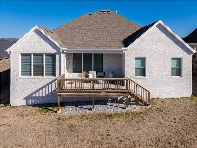 back of house with brick siding, a shingled roof, and a deck