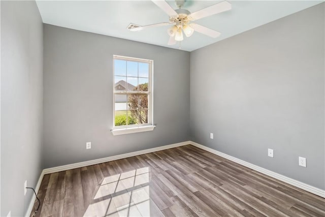 spare room featuring baseboards, wood finished floors, visible vents, and a ceiling fan