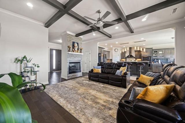 living area featuring dark wood finished floors, visible vents, a stone fireplace, and beam ceiling