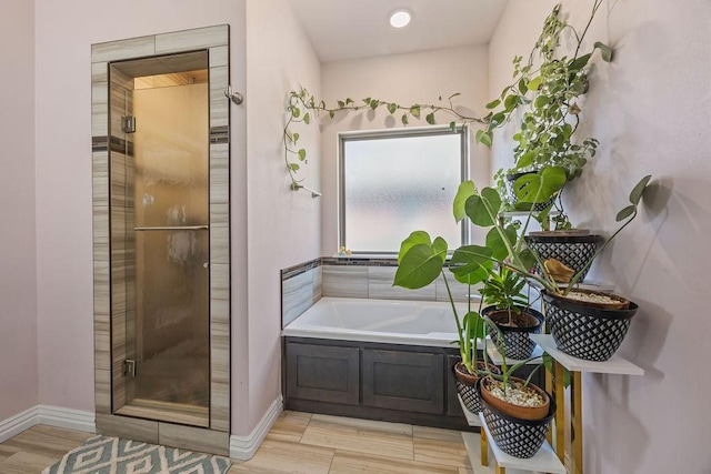 full bathroom featuring wood finished floors, baseboards, a garden tub, and a stall shower