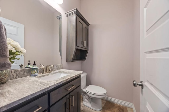 bathroom with toilet, vanity, and baseboards