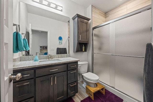 bathroom with toilet, a stall shower, and vanity