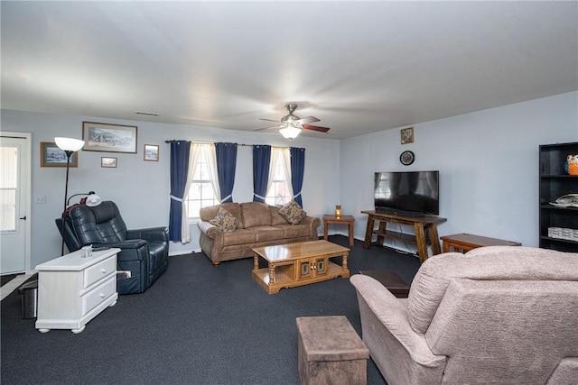 living area featuring visible vents, dark carpet, and a ceiling fan