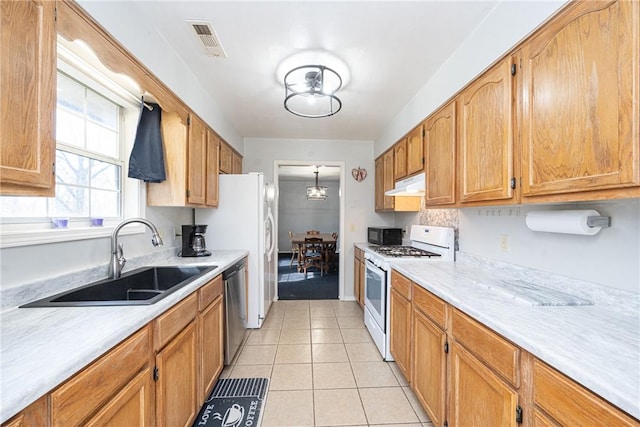 kitchen featuring visible vents, under cabinet range hood, white gas range oven, stainless steel dishwasher, and a sink