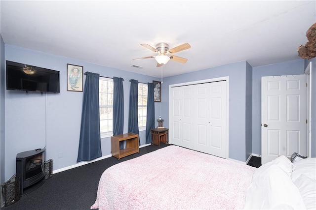 bedroom featuring a wood stove, baseboards, visible vents, and a closet